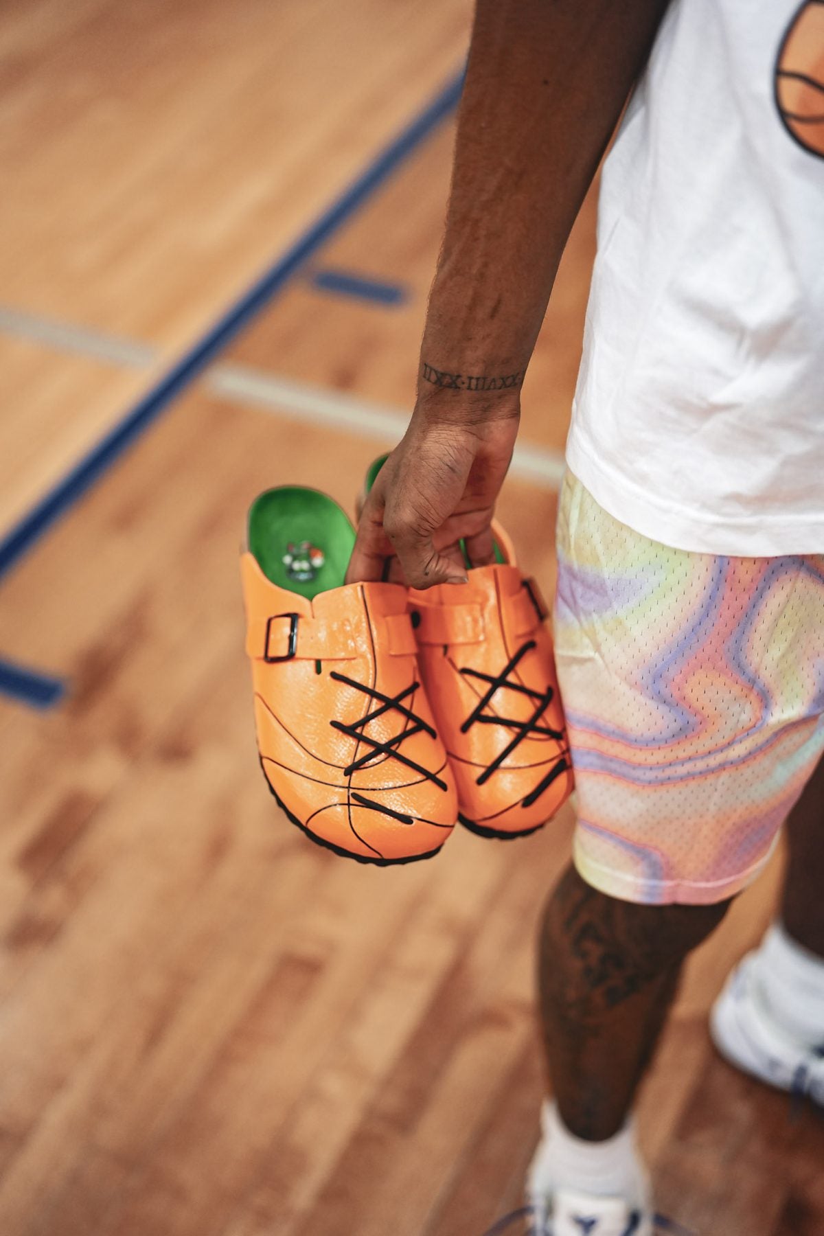 Hand carrying a pair of WB-001 clogs courtside